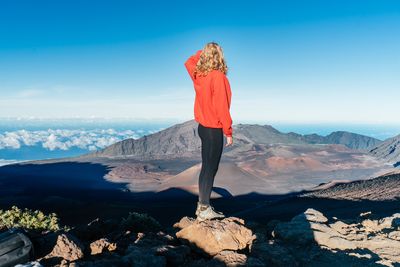 Rear view of woman standing on rock against mountains