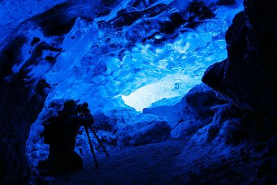 Rear view of photographer photographing ice cave