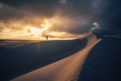 Scenic view of sand dunes against sky during sunset