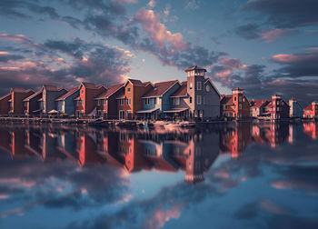 Panoramic view of sea and buildings against sky at sunset