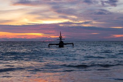 Silhouette boat sailing in sea against sky during sunset