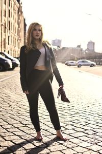 Full length portrait of young woman walking on street in city