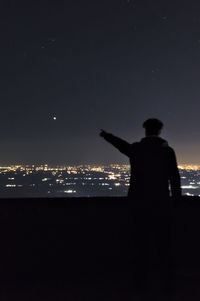 Rear view of man with cityscape in background at night