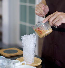 Close-up of hand holding ice cream cone on table