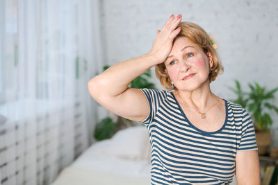 Unhappy mature woman touching her head while feeling severe headache while