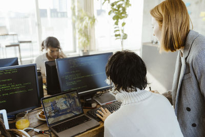 Manager discussing with programmer over computer at desk in office