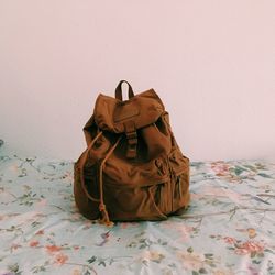 Brown backpack on bed by wall in room