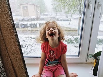 Full length of girl sitting on window