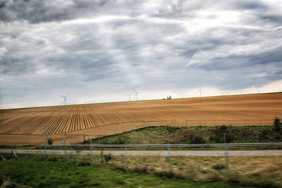 Scenic view of field against cloudy sky