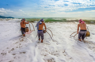 Men fishing in sea against sky