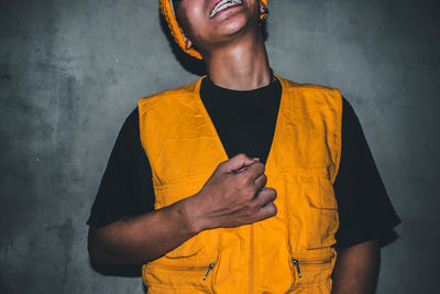 Young man standing against yellow wall