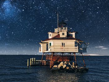 Built structure by sea against sky at night