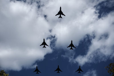 Low angle view of silhouette birds flying against sky