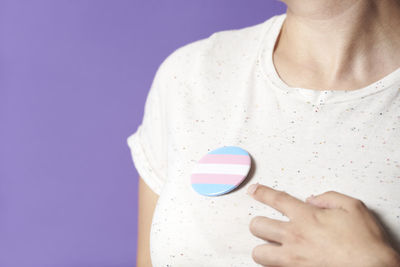 Midsection of woman holding heart shape against blue background