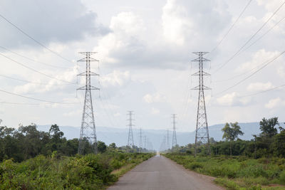 Electricity pylon by road against sky