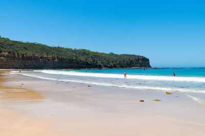 Scenic view of beach against clear blue sky