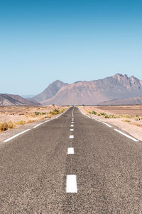 Road leading towards mountains against sky