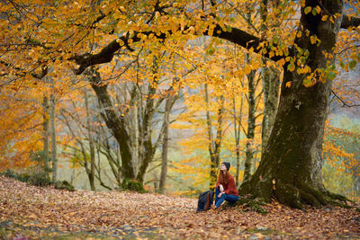 Woman sitting in forest during autumn