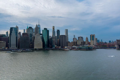 Sea by modern buildings against sky in city