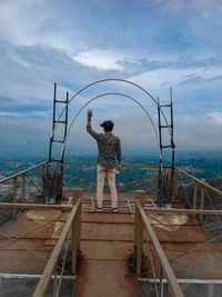 Rear view of man standing by railing against sea