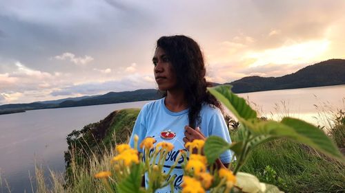 Young woman looking at camera against sky during sunset