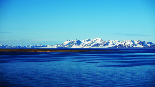 Scenic view of snowcapped mountains against blue sky