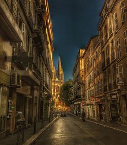 Street amidst illuminated city against sky at night