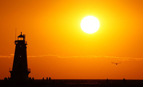 Silhouette bird by sea against sky during sunset