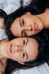 Close-up portrait of sisters lying on bed