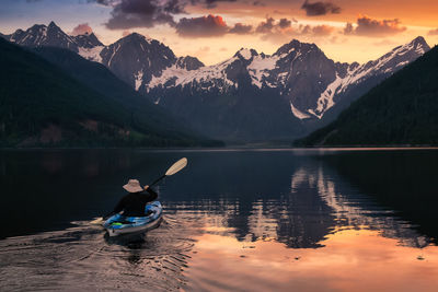 Man in boat on lake against mountains