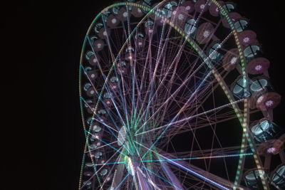 Close-up of illuminated ferris wheel against black background