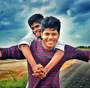 Portrait of smiling young couple standing against sky