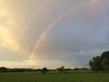 Scenic view of field against rainbow in sky