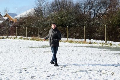 Portrait of young man standing on snow covered field getting ready to throw snowballs 