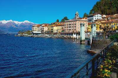 View of buildings by sea against blue sky