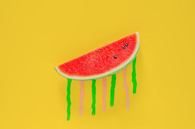 Watermelon with poster color drop on yellow background. minimal summer fruit concept.