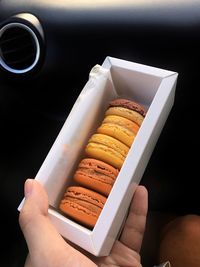 Close-up of hand holding macaroons in box
