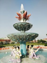 People by fountain against sky in city