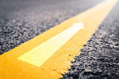Close-up of yellow arrow symbol on road