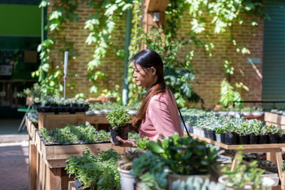 Portrait of young woman standing by plants