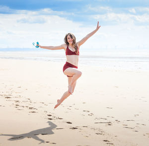 Full length of young woman jumping on beach