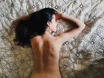 Directly above shot of sensuous topless woman lying down on bed