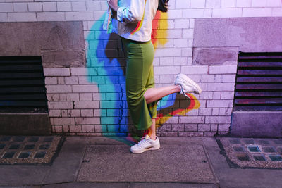 Woman standing on one leg in front of brick wall