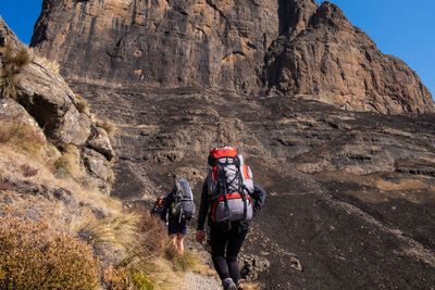 Rear view of people walking on rock