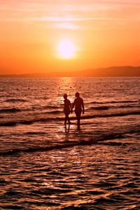 Silhouette of people on beach at sunset