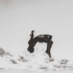 Low angle view of man jumping against sky