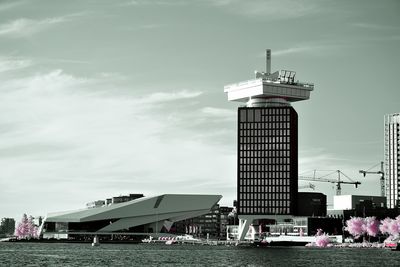 Lighthouse by buildings against sky in city