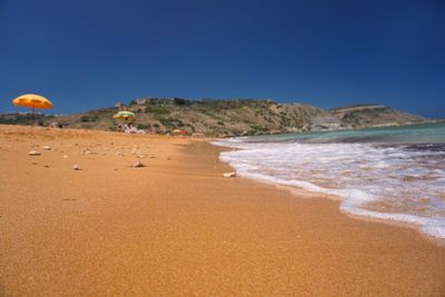 Scenic view of beach against clear blue sky