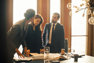 Male and female legal professionals discussing over documents at office meeting