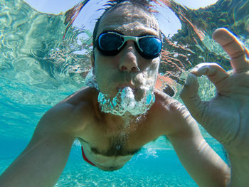 Portrait of man gesturing ok sign while swimming in pool